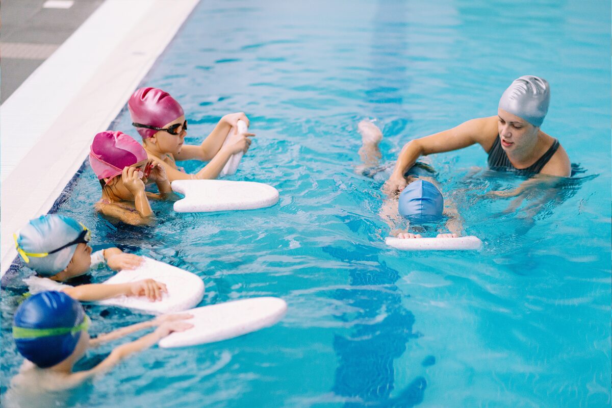 Kinder üben mit Schwimmbrettern